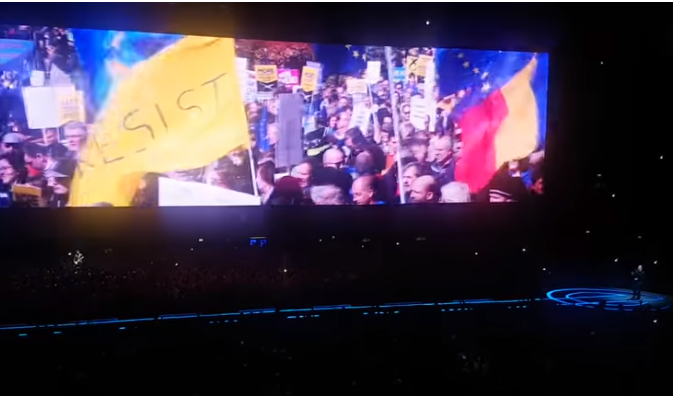 Imagine de la un protest din România într-un montaj ce apare în concertele celebrei trupe U2