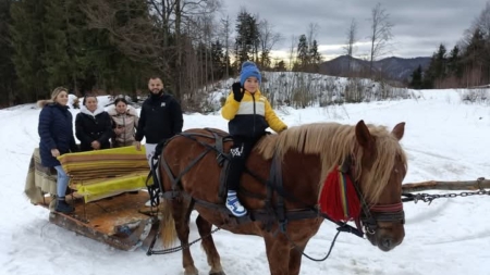 Turiști fericiți după o plimbare cu sania, trasă de iapa Karina